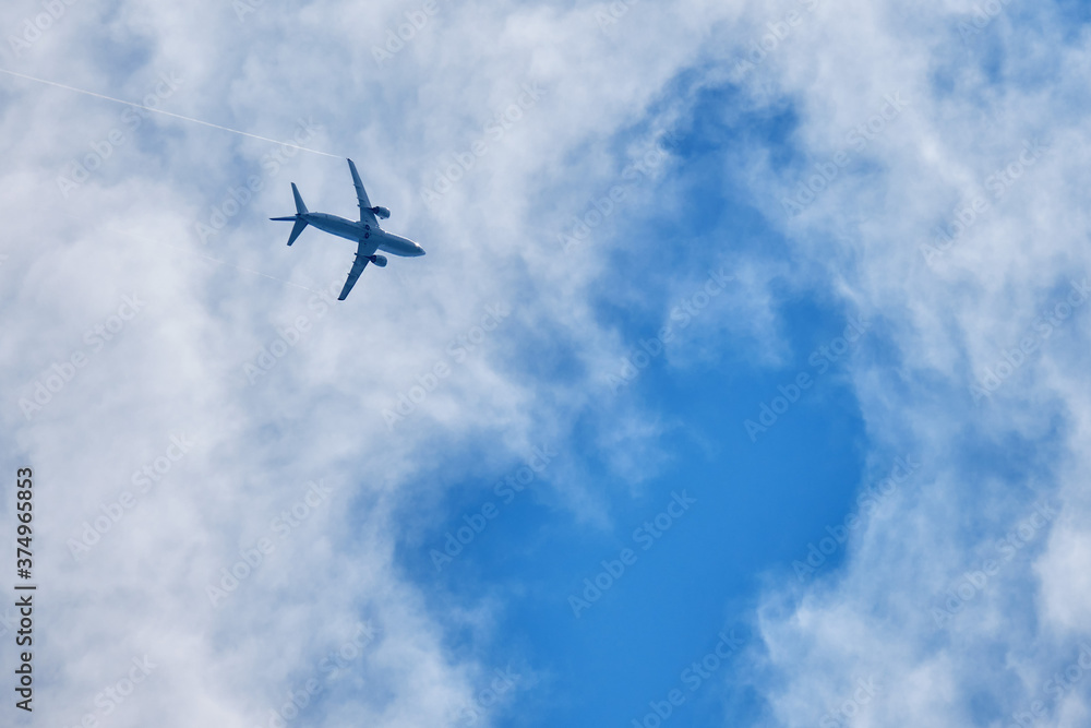 Plane in a blue sky with clouds, view from below Plane in a blue sky with clouds, view from below