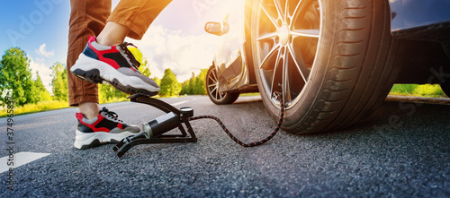 Quadro em tela Driver using a foot pump to inflate a tire