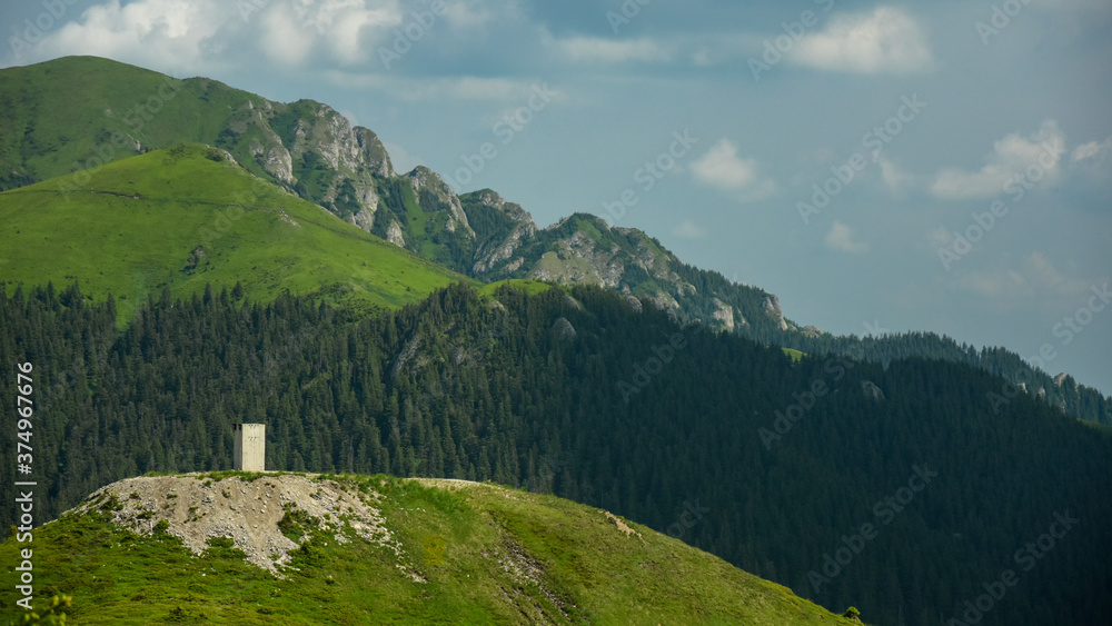 A concrete tower in the alpine grassland of Ciucas Mountains. In the bacground can be seen Ciucas peak and its cliffs.