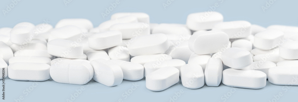 many white capsule tablets or pills on blue table. Close up. Healthcare pharmacy and medicine concept with copy space Painkillers or prescription drugs consumption. Medical Web banner many white capsule tablets or pills on blue table. Close up. Healthcare pharmacy and medicine concept with copy space Painkillers or prescription drugs consumption. Medical Web banner