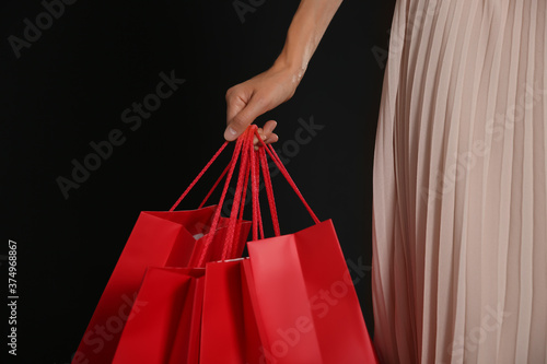 Young woman with shopping bags on dark background, closeup. Black Friday Sale