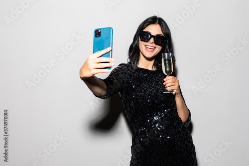 Photography Portrait of a cheerful happy girl, dressed in a black dress, taking off herself, isolated on a white background
