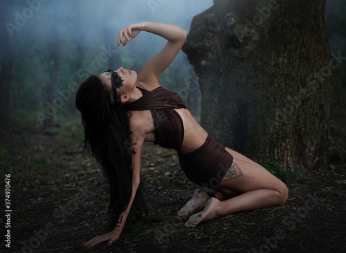 Ritual dance of an Amazon girl near a tree in smoke. Shaman girl with long black hair