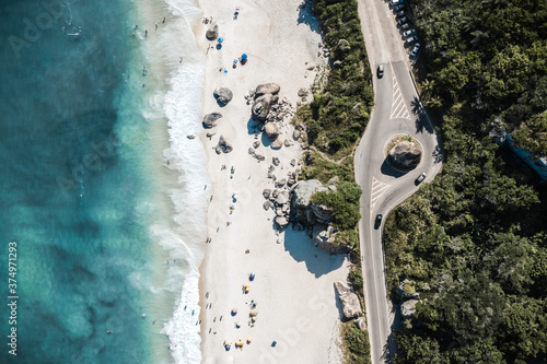 Aerial View Of Cars Driving On Coastal Road Through Forest Along Shore Of Tropical Beach In Rio De Janeiro, Brazil photo