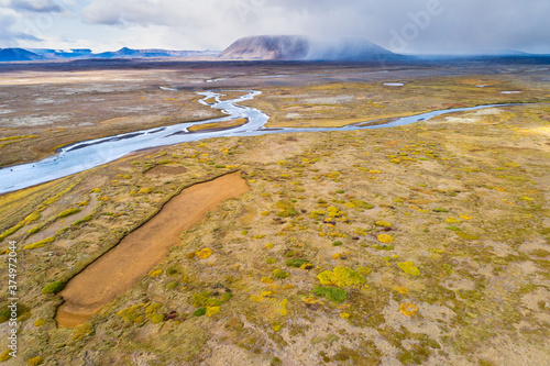 Aerial view of Svarta river and low vegetation in front of Kjalfell mountain with rain showers in the Kjolur area in the highlands of Iceland photo