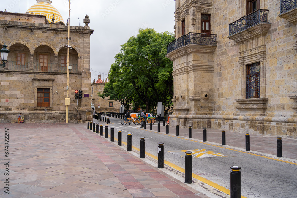 Dos hombres van con sus bicicletas y sus mercancías por la calle Morelos del centro histórico de Guadalajara. 