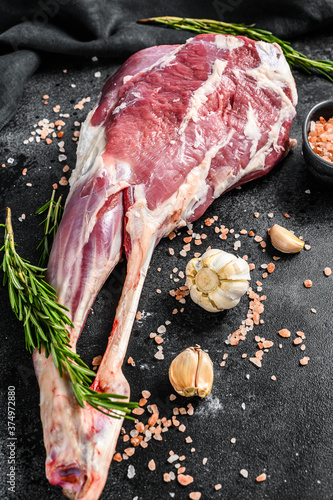 Whole lamb leg. Raw organic meat. Black background. Top view