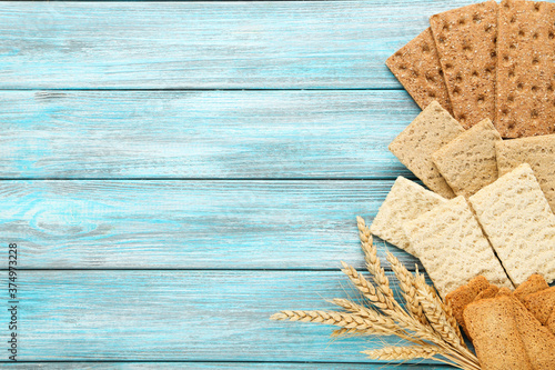 Tableau sur toile Tasty crispbread with wheat ears on blue wooden table