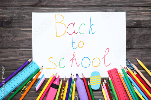 Different school supplies with text Back to School on wooden background