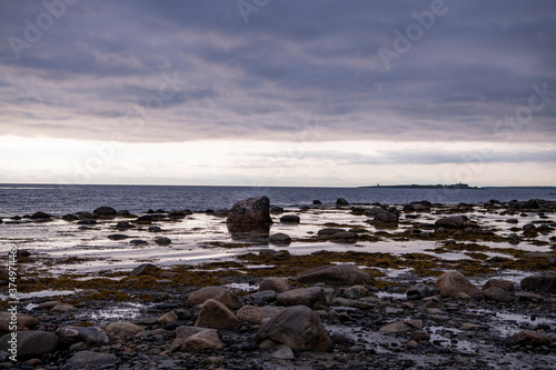 landscape with sea and coastline against the background of blue clouds and the setting sun on the northern island