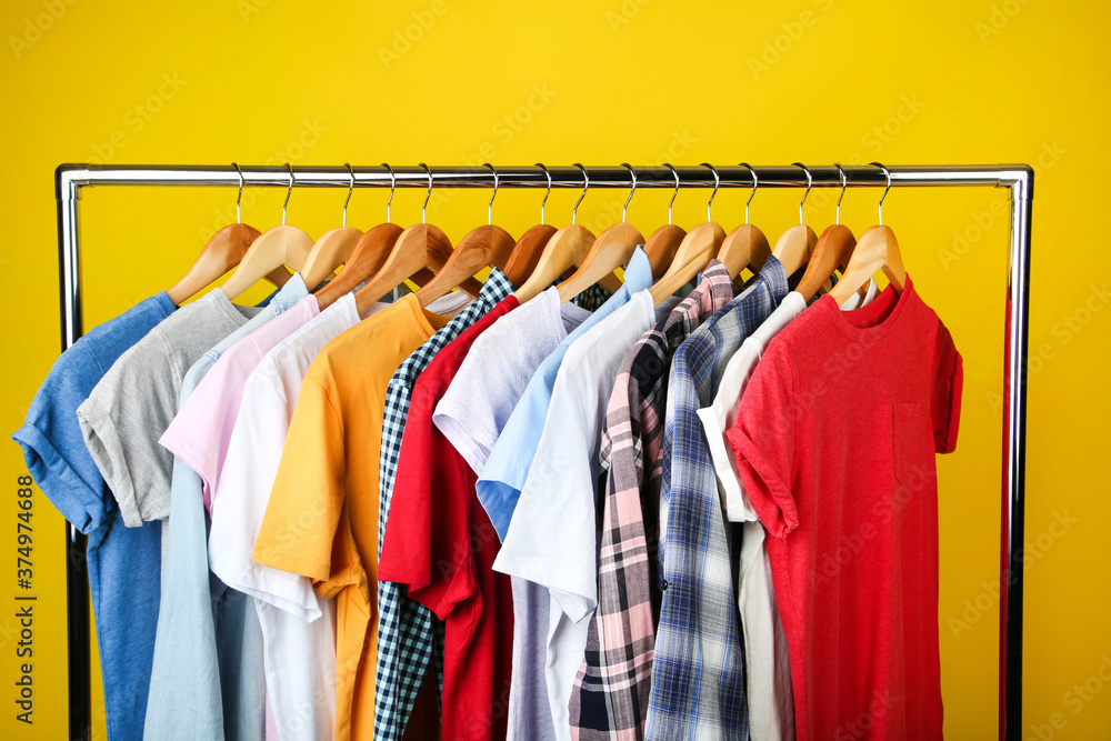 Obraz premium Wooden hangers with clothes on yellow background