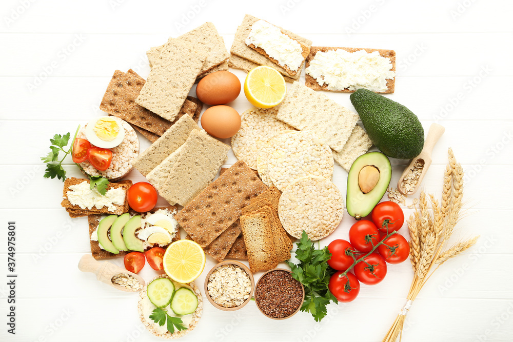 Crispbread with cream cheese, eggs and vegetables on white wooden table