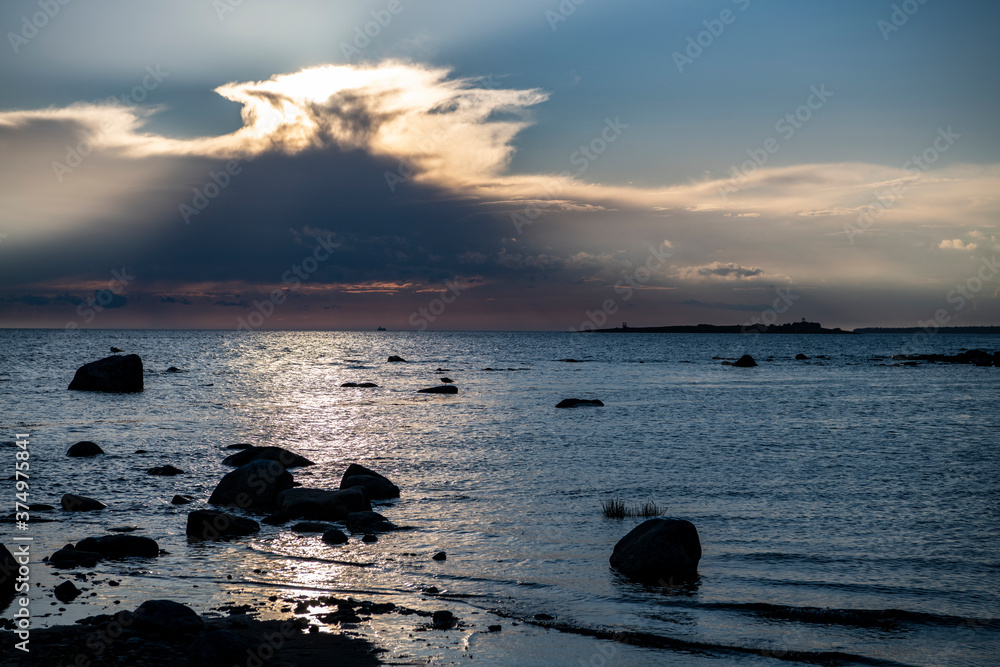 landscape with sea and coastline against the background of blue clouds and the setting sun on the northern island