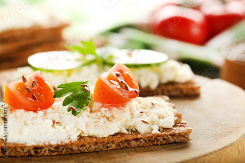 Crispbread with cream cheese, tomatoes and green parsley on brown board