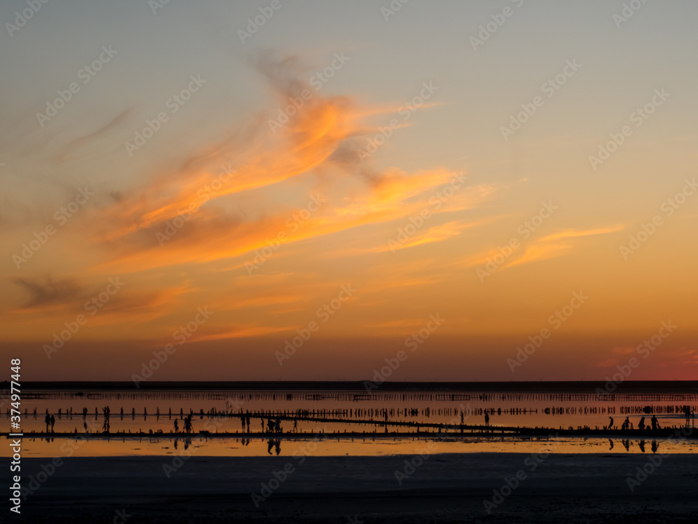 Dramatic lake over the sunset. Peoples resting on the salt lake in europe. Burning sun flare