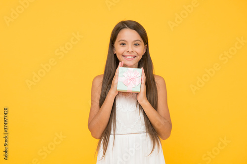 Online shop. boxing day concept. small child on yellow background. holiday shopping sales. beauty box. surprise for birthday. long awaited present. happy childhood. cheerful little girl hold gift box