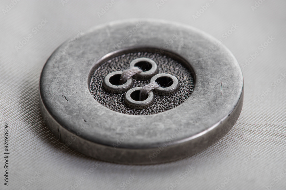 a metal button with a slotted swept loop on the flap of the raincoat sleeve made of beige fabric a metal button with a slotted swept loop on the flap of the raincoat sleeve made of beige fabric