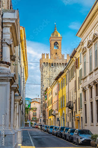 Typical italian street with parked cars and Torre della Pallata brick medieval tower building background, Brescia city historical centre, vertical view, Lombardy, Northern Italy