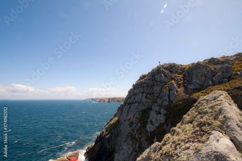 A lonely persone standing on a cliff above sea photo