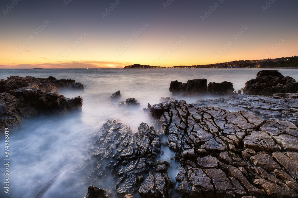 Obraz premium Sea shore with rocks at sunset. Seascape in summer time. Rocks and water. Long exposure. Mediterranean sea. Travel - image.