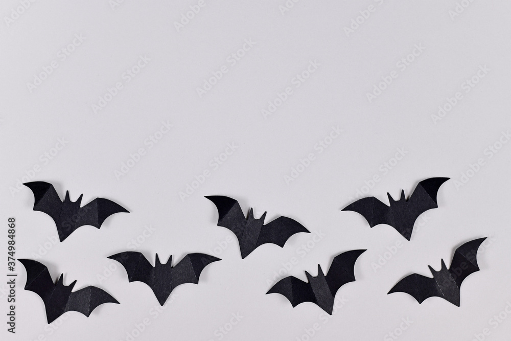 Black papercraft flying Halloween bats at bottom of gray background with empty copy space Black papercraft flying Halloween bats at bottom of gray background with empty copy space