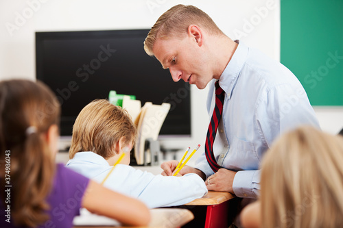 Classroom: Male Teacher Assisting Schooboy with Assignment photo