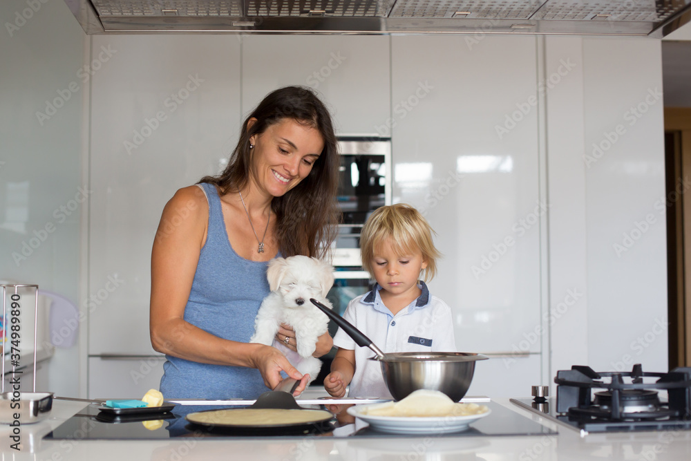 Cute toddler child and mom, mother and blond boy, making pancake in kitchen Cute toddler child and mom, mother and blond boy, making pancake in kitchen