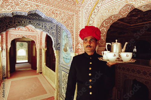 India, Jaipur, Samode Palace, waiter with tea tray in ornate hallway photo