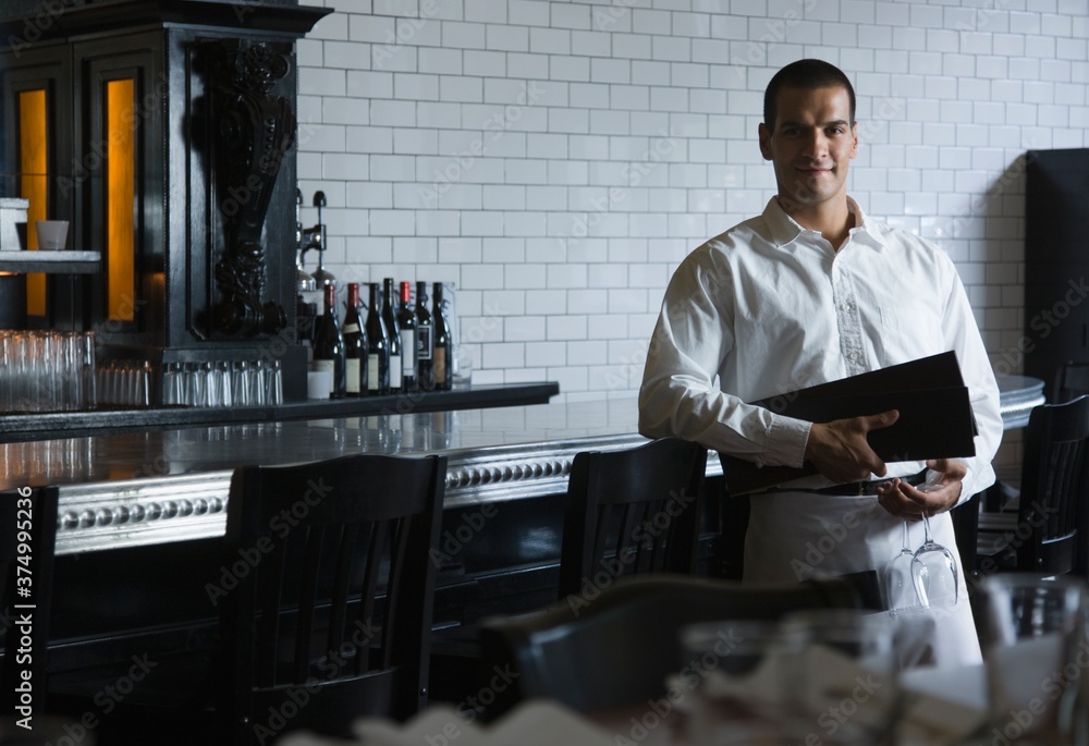 Portrait of waiter holding menu and wine glasses in restaurant Portrait of waiter holding menu and wine glasses in restaurant