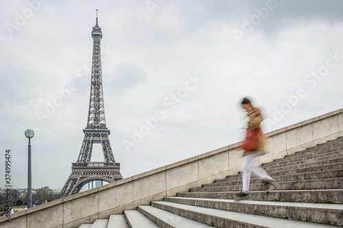 A woman walking down the stairs with the Eiffel Tower in the background photo