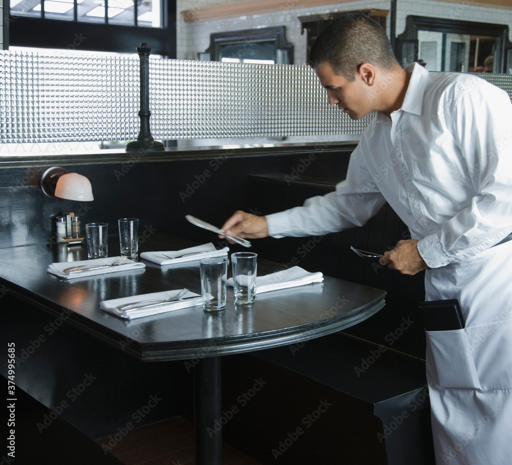 Waiter arranging table in restaurant Waiter arranging table in restaurant