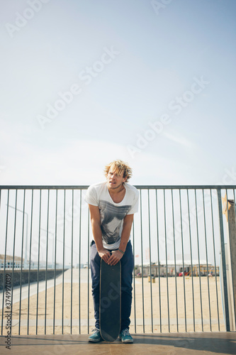 Skater standing on a half-pipe with his skateboard photo