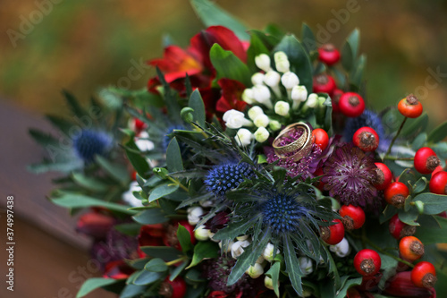 Autumn wedding bouquet created from various flowers and berries and two wedding rings © karinabost