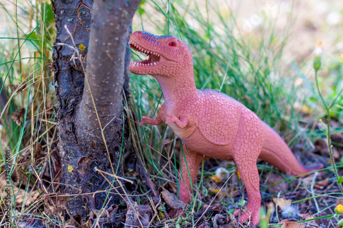 Toy dinosaur in the thicket imitates the natural environment. Toy for children.