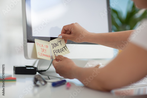 Woman sticking post it reminders on her desktop monitor.