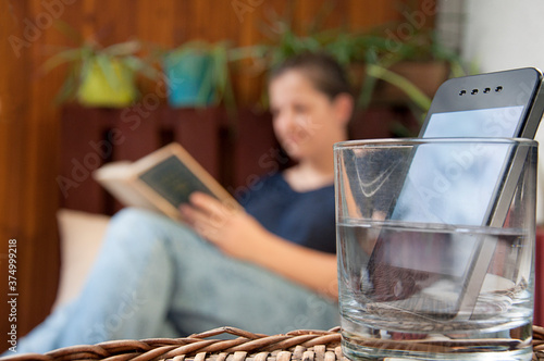 digital detox_smartphone_glass with water_woman reading_by jziprian photo