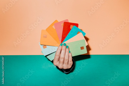 Hand coming through a wall holding several credit cards