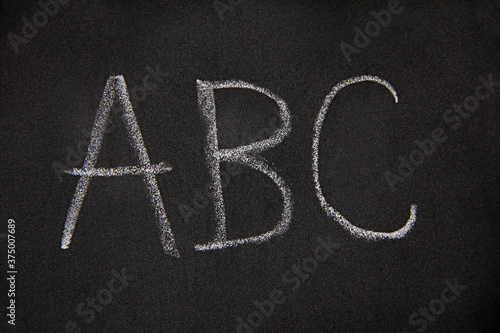 the letters A, B, C isolated on black, closeup of first english alphabet letters written on a blackboard with a piece of chalk