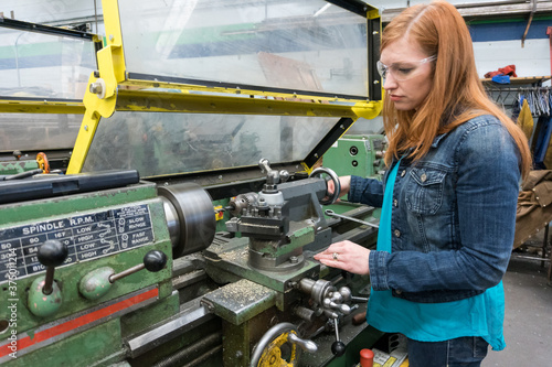 Female company executive tries out lathe in machine shop photo