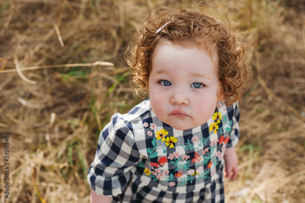 Read haired toddler looking up at camera Read haired toddler looking up at camera