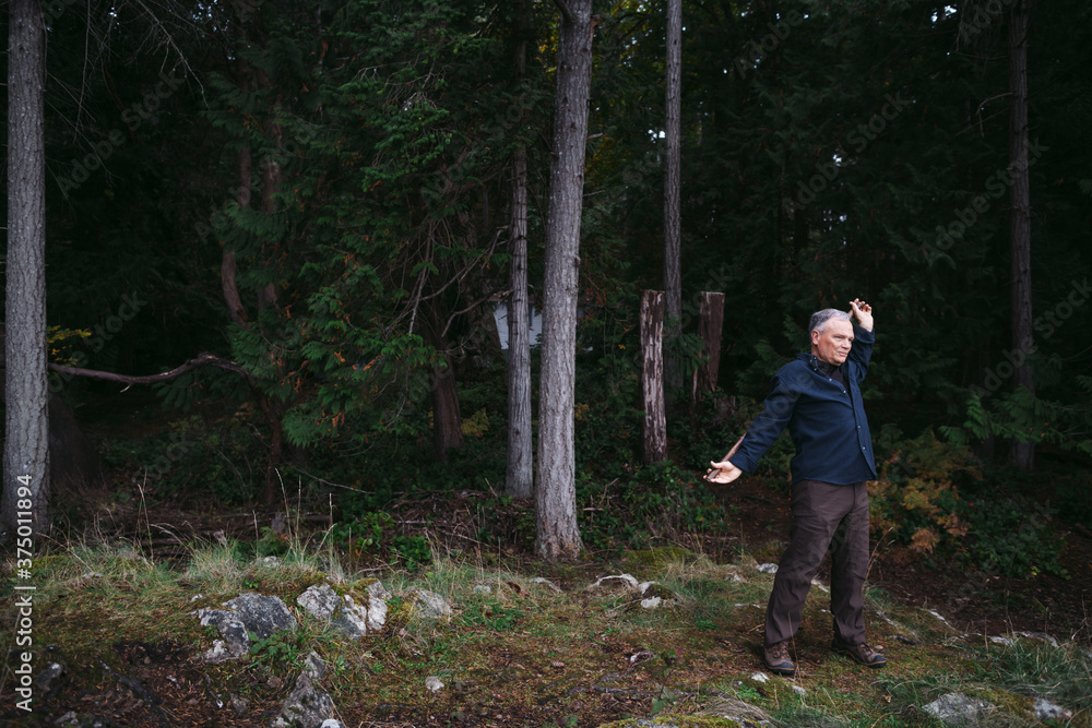 Mature man in rugged nature practicing Chinese Wand routine.. Mature man in rugged nature practicing Chinese Wand routine..