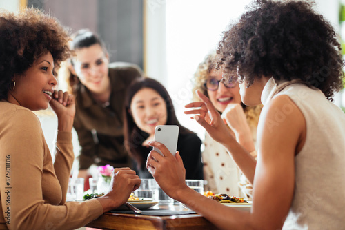 Black woman showing smartphone to diverse friends