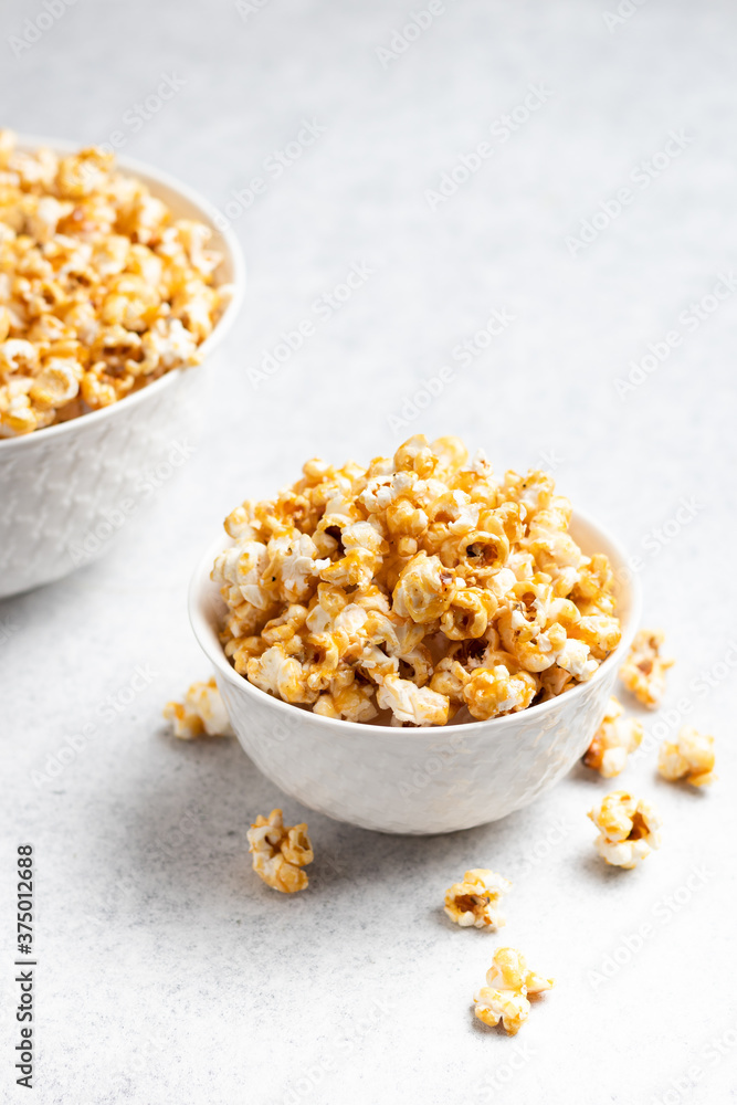 caramel popcorn in a white bowl with a big bowl in the background caramel popcorn in a white bowl with a big bowl in the background