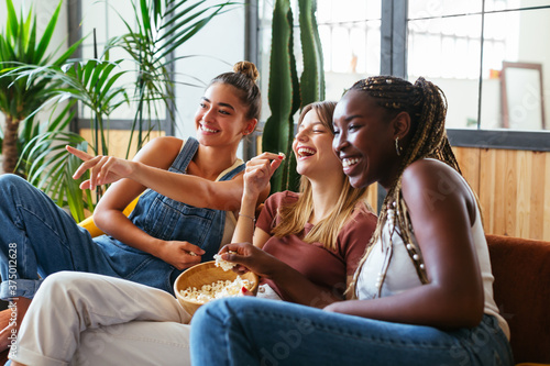 Cheerful diverse teenagers watching comedy at home photo