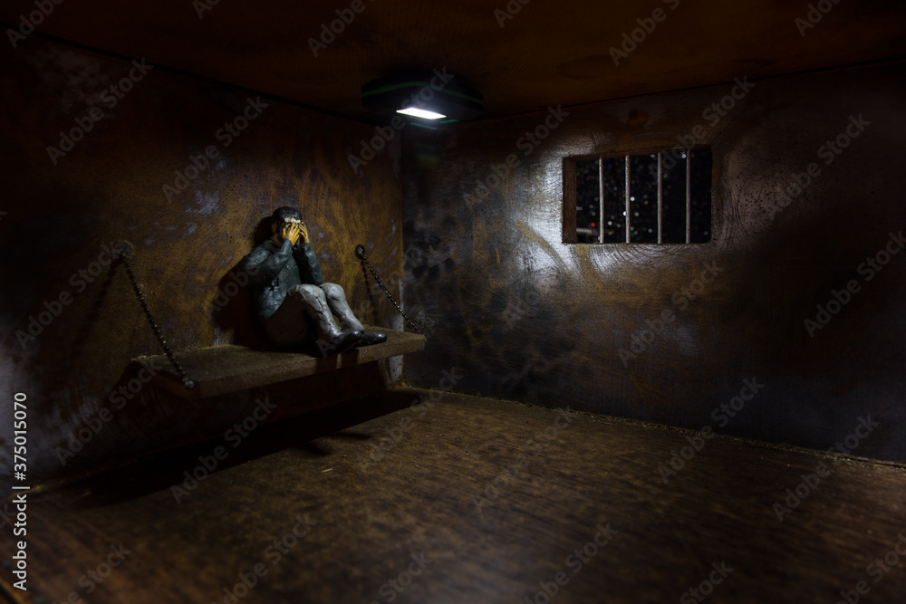 Jail or prison cell. Man in prison man behind bars concept. Old dirty grunge prison miniature. Dark prison interior creative decoration. Selective focus Jail or prison cell. Man in prison man behind bars concept. Old dirty grunge prison miniature. Dark prison interior creative decoration. Selective focus