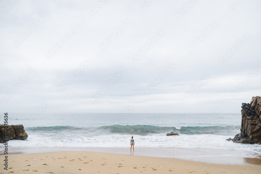 Young girl staring at large, incoming wave. Young girl staring at large, incoming wave.