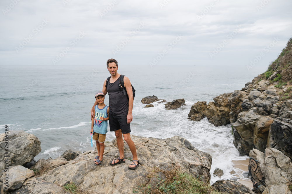 Father and son looking at camera near cliff and ocean. Father and son looking at camera near cliff and ocean.