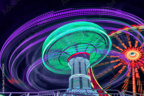 Fun for teens and family. A long exposure of a amusement park with a chain carusel in a very dynamic rotation in the late hours of the day. photo