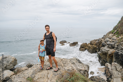 Father and son looking at camera near cliff and ocean. photo