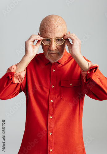 Bald Senior Man putting on eyeglasses photo